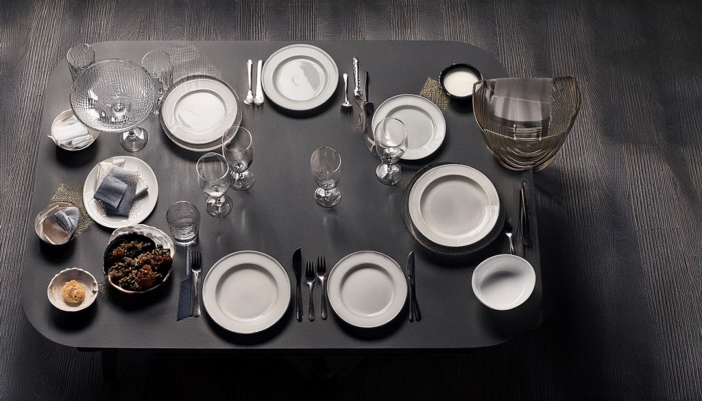 Pratos, copos e talhares elegantemente dispostos sobre mesa preta