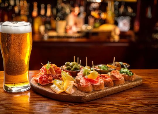 Firefly Prato de tapas espanholas com um copo de cerveja em cima de um balcão de madeira. Mostra ist