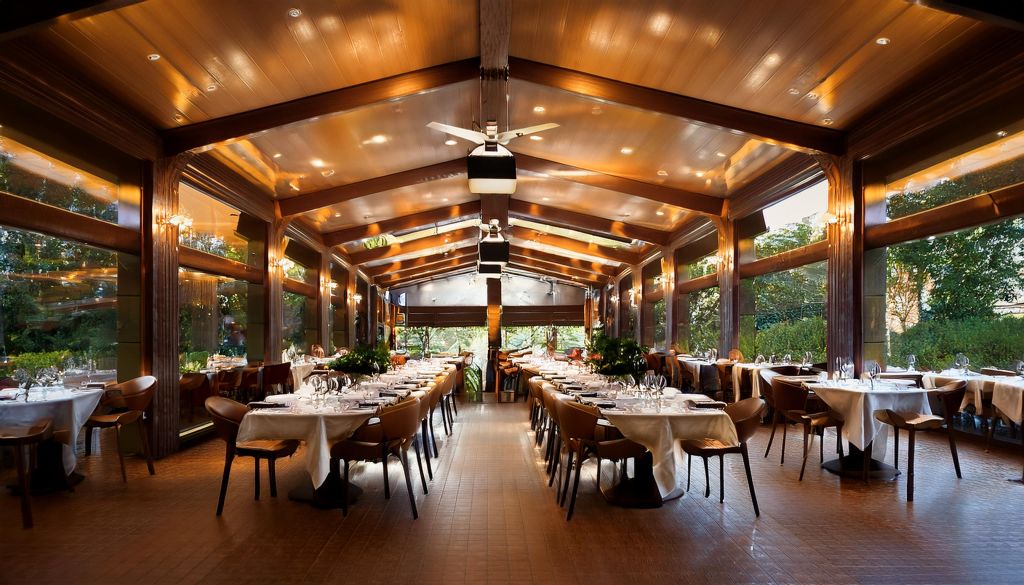 Interior de uma sala de restaurante com quatro filas de mesas alinhadas